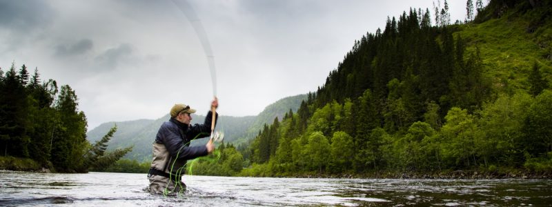 Fluefisker kaster i elv omgitt av grønn fjelldal